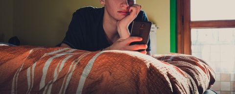 Teenager using phone in bedroom header with overlay