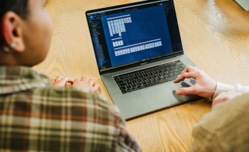 Two individuals collaborating on a laptop, focused on their work and sharing ideas in a bright, inviting workspace.