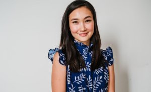 Woman smiling warmly towards camera in blue chiffon shirt