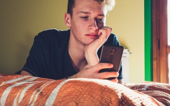 Teenager using phone in bedroom Client story header