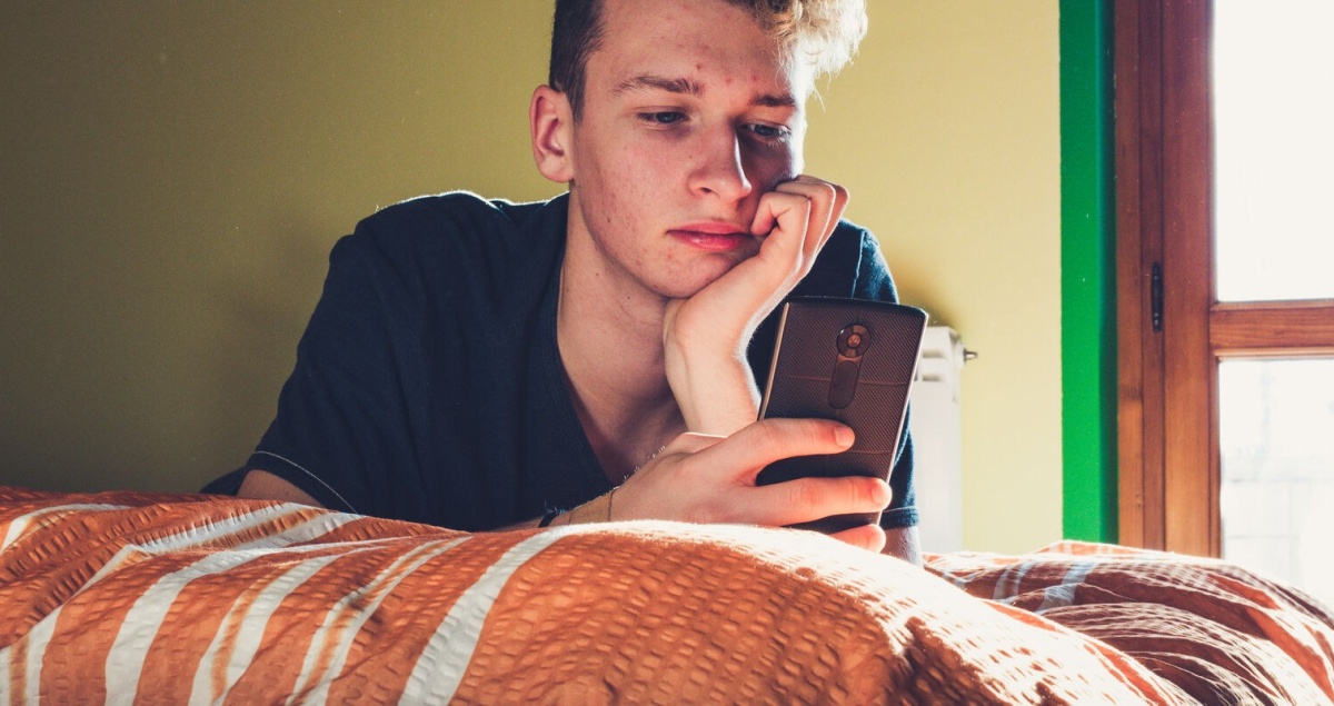 Teenager using phone in bedroom Client story header