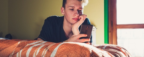 Teenager using phone in bedroom Client story header